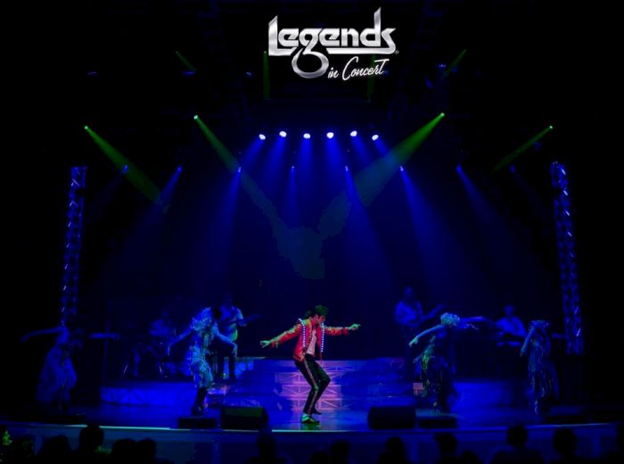 A live concert performance is taking place on stage with dancers and vibrant lighting. The title "Legends in Concert" is displayed at the top.